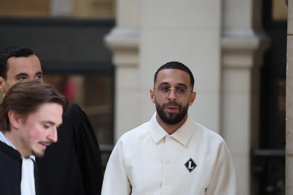 Le rappeur Naps devant le tribunal accompagné de personnes en robe noire.