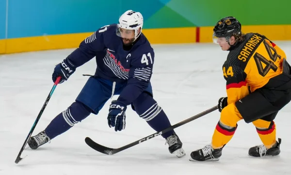 Un joueur de la France et un joueur de l'Allemagne se disputent la rondelle.