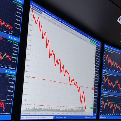 Graphique boursier affichant une chute brutale du prix exactement à 10h00, ligne rouge verticale descendant sur fond d'écran de trading avec multiples graphiques et chiffres en temps réel, ambiance de salle de marché sous éclairage bleu froid