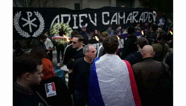 Rassemblement en hommage à Quentin avec bannière et couronne de fleurs.