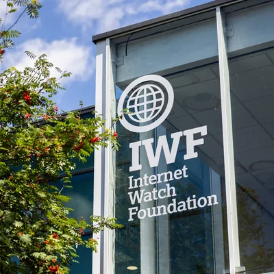 Vue extérieure du bâtiment de l'Internet Watch Foundation (IWF) avec son logo sur la façade vitrée.