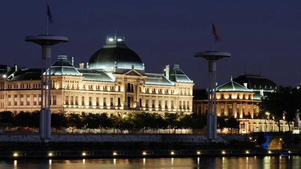 Un bâtiment historique illuminé de l'Université Lumière Lyon 2 reflété dans l'eau.