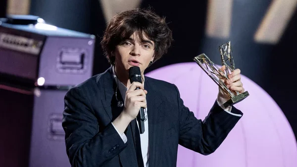 Sam Sauvage avec sa Victoire de la Musique, en costume noir