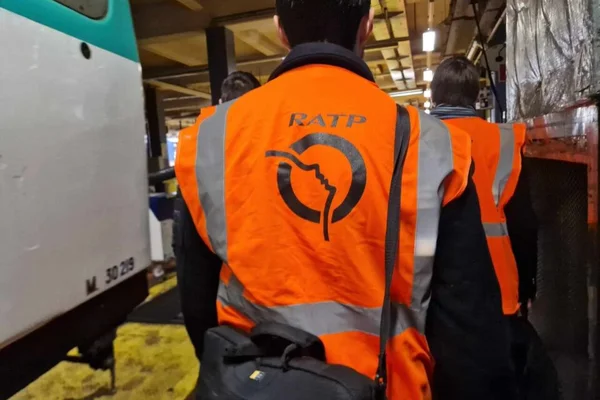 Des agents de maintenance RATP en gilet orange dans un atelier technique.
