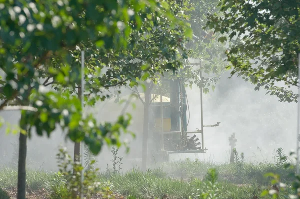 Worker in protective gear spraying pesticides on crops in an agricultural field