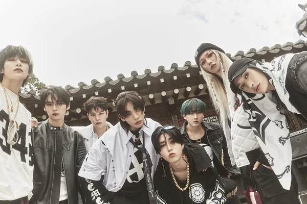 Stray Kids en tenues décontractées devant un bâtiment traditionnel coréen.