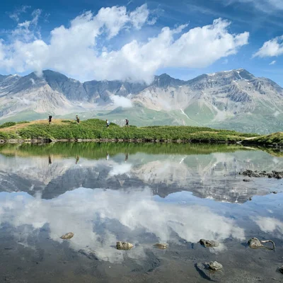 Paysage de montagne avec un lac et des randonneurs au bord de l'eau dans la Vanoise