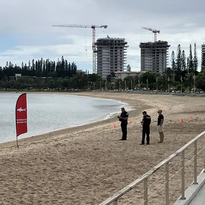 Drapeau d'avertissement requin et autorités sur la plage de l'Anse Vata, fermée suite à l'observation de requins.