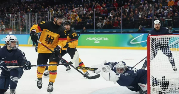 Action de jeu lors de l'Allemagne-France aux JO 2026, avec un joueur allemand et un gardien français.