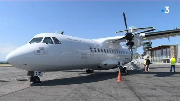 Un avion de ligne stationné sur le tarmac avec du personnel en gilet jaune à proximité