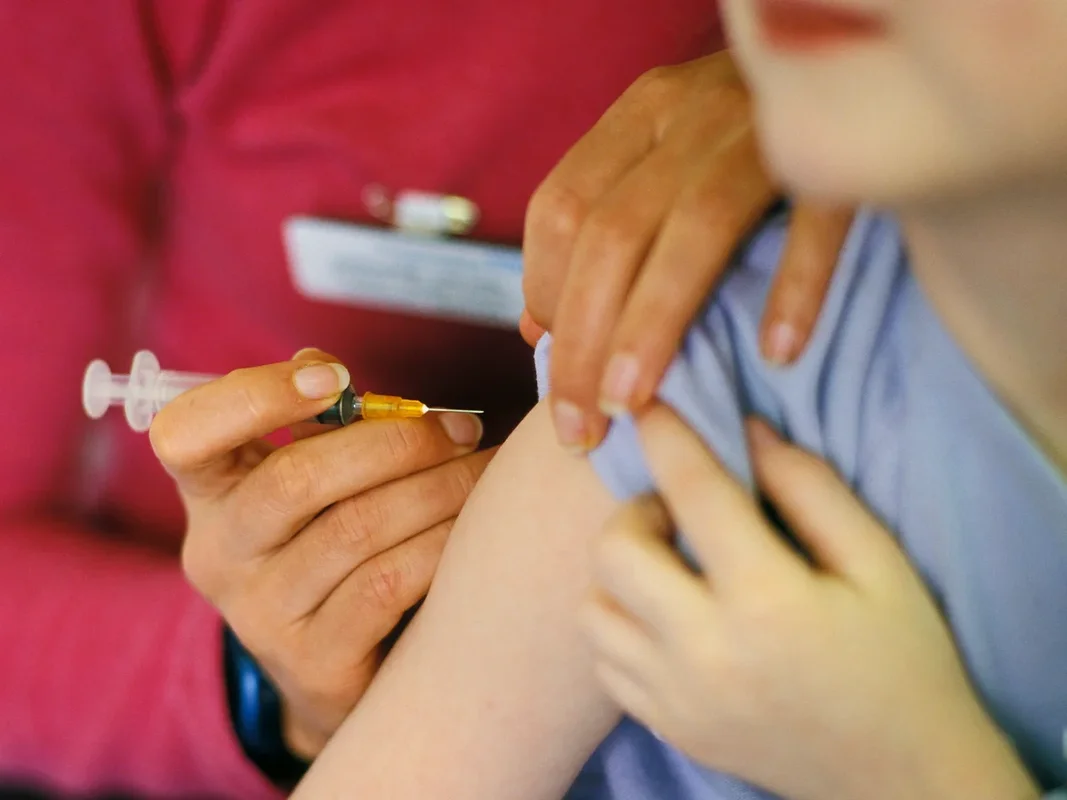 Un professionnel de santé préparant une injection sur le bras d'un enfant.