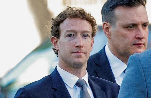 Mark Zuckerberg en costume bleu marine et cravate grise, un autre homme en costume visible en arrière-plan