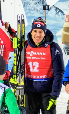 Quentin Fillon Maillet, biathlète français, en tenue de compétition avec ses skis Fischer.