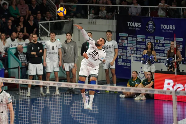 Un joueur de volley-ball saute pour smasher un ballon devant des spectateurs.