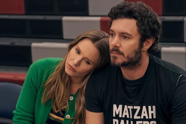 Adam Brody and Kristen Bell seated together in a gym setting for the Netflix romantic comedy series Nobody Wants This.