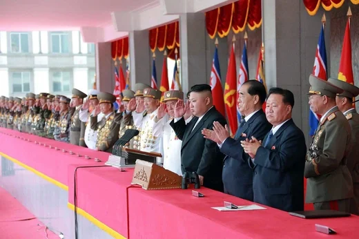 Kim Jong Un in a dark suit pointing next to a military officer
