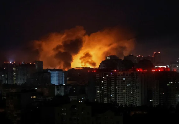Un grand incendie avec des flammes orange vif et une épaisse fumée visible dans une zone urbaine ukrainienne pendant la nuit