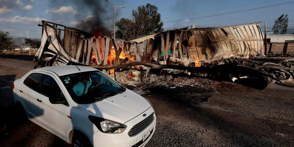 Un véhicule en proie aux flammes et renversé sur une route.
