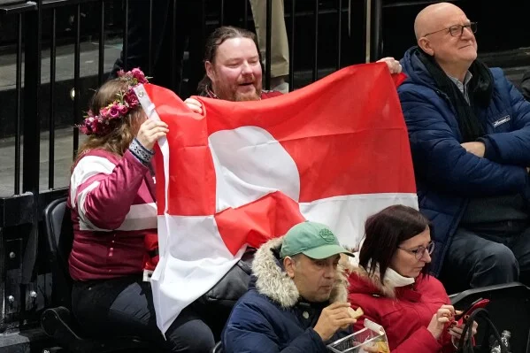 Crowd in hockey stadium waving Greenland flags.