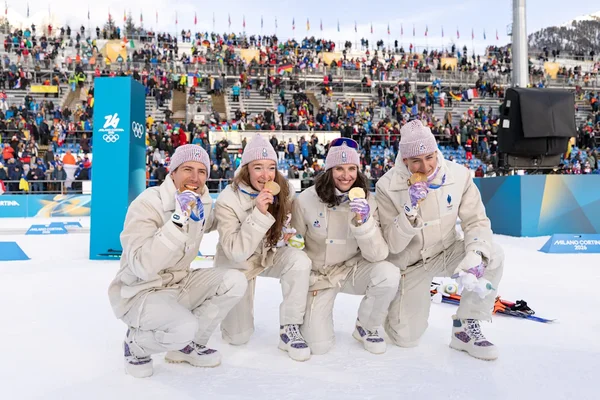 Quatre médaillés français en uniforme blanc souriant avec leurs médailles aux JO 2026