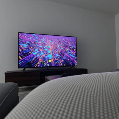 Écran de télévision moderne affichant un jeu vidéo en haute définition avec des couleurs vives, flou en premier plan d'un canapé et d'une table basse