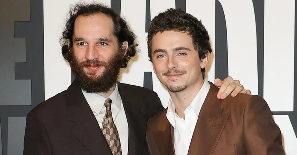 Timothée Chalamet en pleine interview française avec expression concentrée, affiche de Marty Supreme en arrière-plan