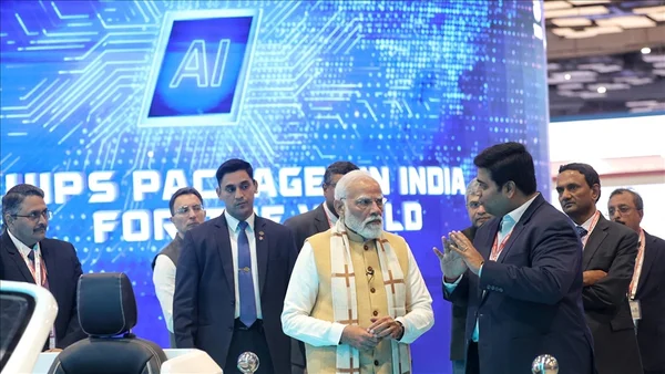 Le Premier ministre Narendra Modi lors du sommet sur l'IA à New Delhi, discutant avec des officiels devant un écran numérique.