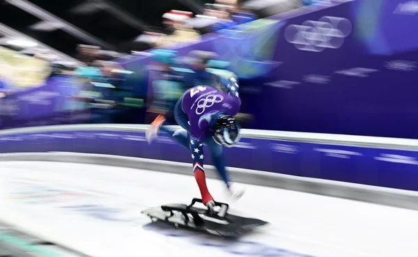 Close up of determined speed skater in red and white suit at starting line.
