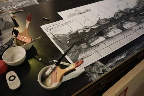 Fournitures d'art et un dessin architectural détaillé en noir et blanc sur une table.