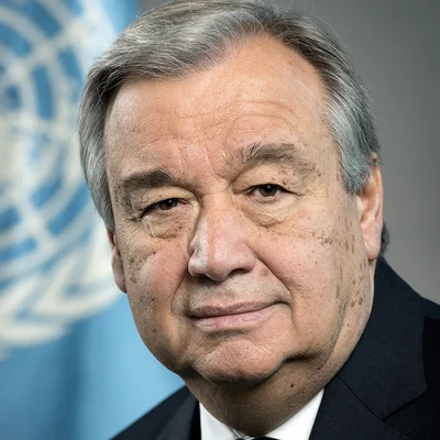 Portrait d'Antonio Guterres, secrétaire général de l'ONU, avec l'emblème des Nations Unies visible.