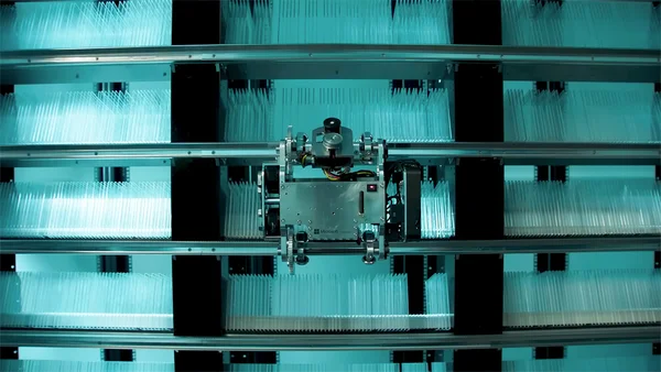 Système mécanique de laboratoire entouré de conteneurs de stockage translucides.