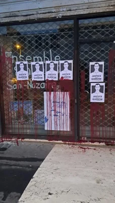 La vitrine d'un local politique couverte de peinture et d'affiches.