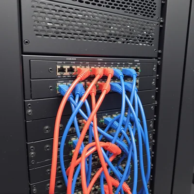 Vue rapprochée d'un serveur informatique avec des câbles lumineux rouges et bleus connectés, indiquant une connexion réseau active dans une salle de serveurs sombre