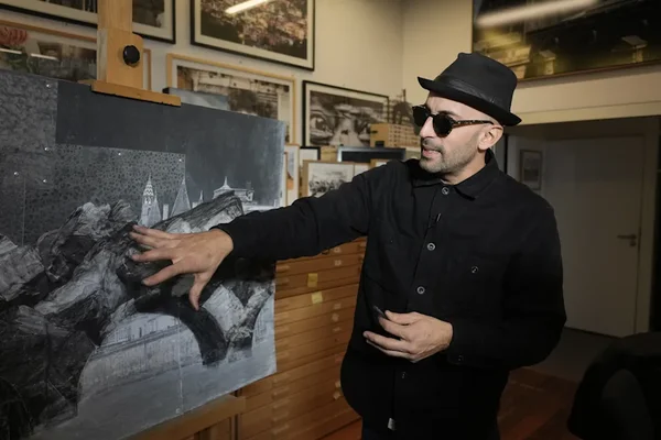 L'artiste français JR travaillant sur une grande peinture en noir et blanc dans son atelier.
