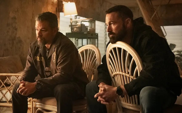 Scene from The Rip showing police officers staring at piles of cash in a run-down house.