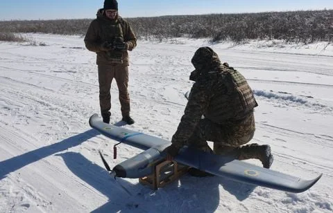 Des opérateurs déploient un drone militaire dans un environnement enneigé en Ukraine