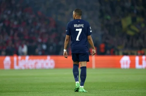 Kylian Mbappe wearing a dark blue PSG jersey with number 7 on a field