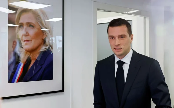 Portrait of Jordan Bardella, President of the National Rally, highlighting controversies regarding his background and party affairs