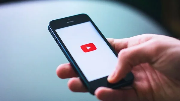 Une main tenant un smartphone affichant l'écran de connexion de YouTube.