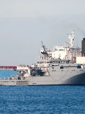 Le navire GRINCH stationné dans une eau bleue calme près d'installations portuaires.