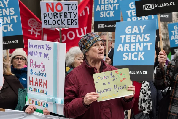 Des manifestants brandissant des panneaux pour et contre les bloqueurs de puberté.