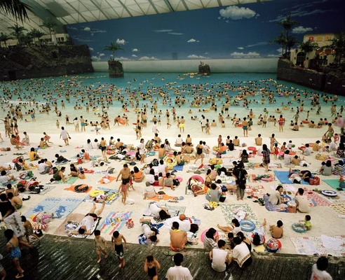 Photographie d'une piscine intérieure très fréquentée, illustrant l'œuvre de Martin Parr sur les loisirs.