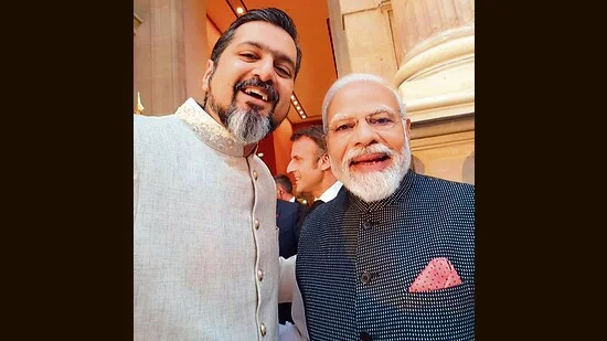 Deux hommes, l'un en kurta et l'autre en costume à carreaux, posant ensemble lors d'un événement formel.