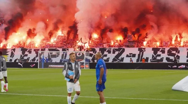 Ambiance inflammable au stade Vélodrome avec des fumigènes rouges lors d'un match de l'OM