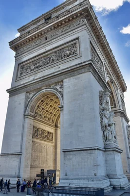 L'Arc de Triomphe illuminé de nuit avec la flamme du Soldat inconnu au premier plan.