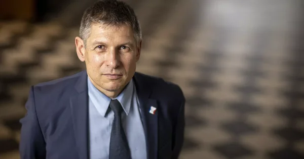 Portrait d'un homme en costume bleu marine avec cravate, posant à l'intérieur