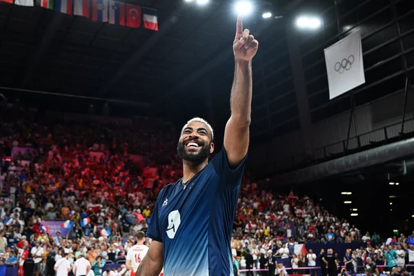 Earvin Ngapeth célébrant dans un stade rempli de spectateurs et de drapeaux.