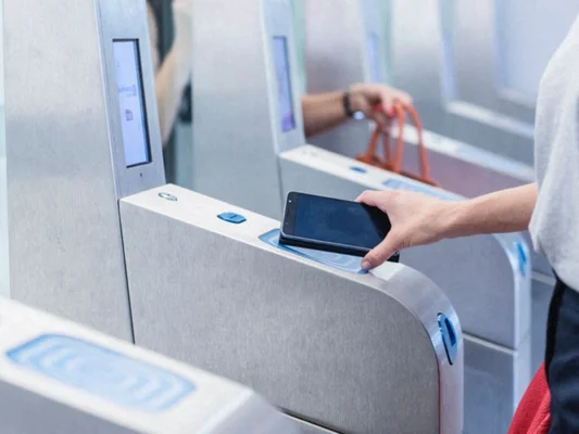 Une main utilise un smartphone sur un terminal de paiement sans contact.