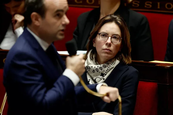 Amélie de Montchalin assiste à une séance dans un cadre parlementaire formel.