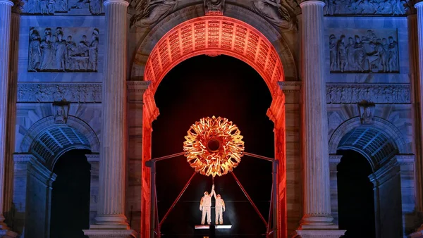 Artistes soulevant une structure en forme de flamme devant l'Architecture de Vérone lors de la cérémonie.
